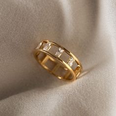 a gold wedding band with three baguettes on the side, sitting on a white cloth