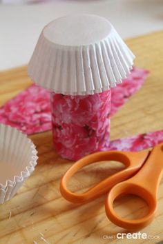 paper cupcake liners and scissors on a cutting board with pink flowers in the background