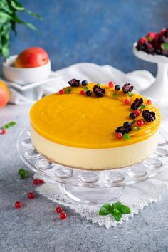 a cheesecake with fruit toppings is on a glass plate next to other dessert items