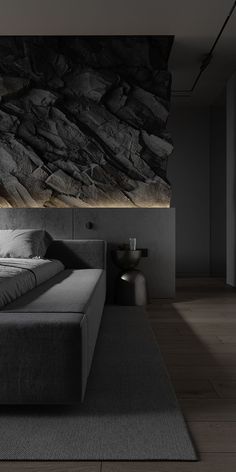 a large bed sitting on top of a wooden floor next to a wall covered in rocks