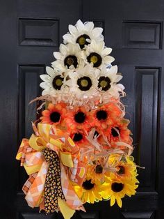 a sunflower wreath is hanging on the front door, decorated with orange and white flowers