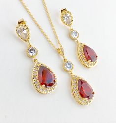 Luxury red ruby cubic zirconia bridal tear drop dangle pendant and necklace in gold plated brass setting. Necklace pendant features a large teardrop with pear cut red ruby cubic zirconia center surrounded by tiny round zirconia crystals and dangles from round cubic zirconia connector and bail. Length of the gold plated chain is 18 inches and comes with 2 inches extender and lobster clasp. For matching earrings click: https://www.etsy.com/listing/667776478/red-crystal-gold-earrings-red-bridal?ref Red Ruby Drop Jewelry, Red Drop Jewelry For Anniversary, Teardrop Gold Plated Necklace For Wedding, Gold Plated Teardrop Necklace For Wedding, Elegant Pear-shaped Ruby Jewelry, Red Gold-plated Jewelry Set For Wedding, Red Pear-shaped Jewelry For Party, Elegant Red Drop Jewelry, Red Pear-shaped Necklace For Gift