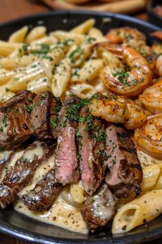 steak, shrimp and pasta on a black plate