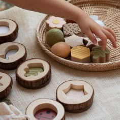 a child's hand reaching for wooden toys in a basket on top of a table