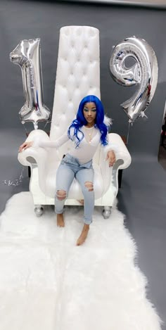 a woman with blue hair sitting in a white chair next to balloons and the number 10