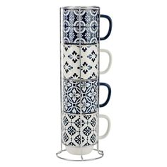 four coffee mugs stacked on top of each other in a metal holder with blue and white designs