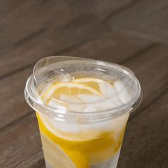 a plastic cup filled with lemonade on top of a wooden table