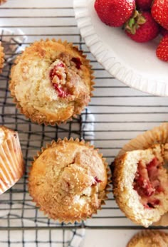 several muffins on a cooling rack with strawberries in the background