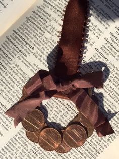 a book with some coins on top of it next to an open book and a brown ribbon