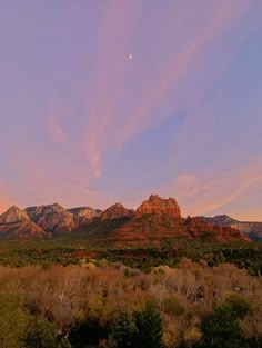 the mountains are covered in trees and bushes as the sun is setting over them,