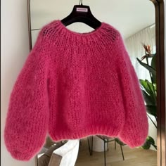 a pink sweater hanging up in front of a mirror