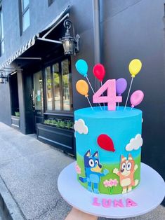 a birthday cake is decorated with cartoon characters on the top and balloons in the middle