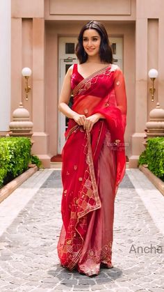 a woman in a red sari is standing outside