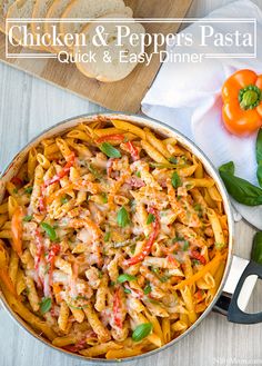 chicken and peppers pasta in a skillet on a wooden table with basil, pepperoni, and bread