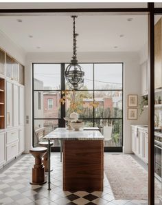 a kitchen with an island in front of a large glass doored window that leads to the outside