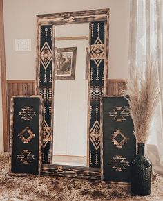 a mirror and vase on a carpeted floor in front of a window with curtains