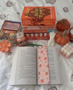 an open book sitting on top of a bed next to candles and other items in front of it