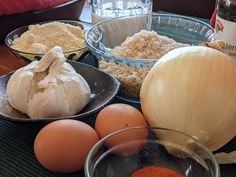 an assortment of ingredients on a table including onions, eggs and breadcrumbs