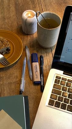 an open laptop computer sitting on top of a wooden table next to a cup of coffee