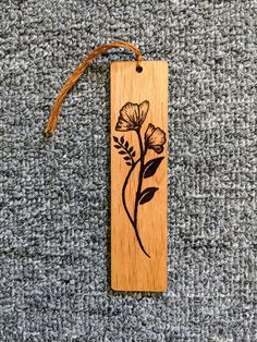 a wooden bookmark with a flower etched on the front and back, hanging from a cord