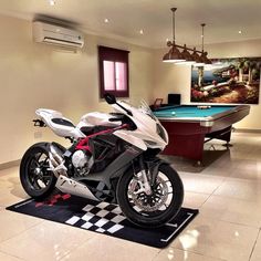 a white motorcycle is parked in front of a pool table and billiards table