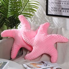 a pink starfish pillow sitting on top of a couch next to a potted plant