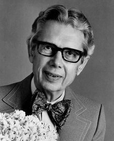 an old man with glasses and a bow tie holding a bouquet of flowers in front of his face