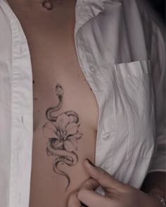 a woman's stomach with a snake and flower tattoo on her left side ribcage