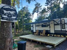 an rv park with picnic tables and chairs next to a tree in front of it