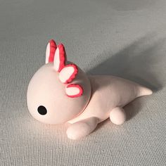 a white stuffed animal laying on top of a white surface with pink and red decorations