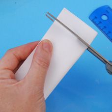 someone is cutting paper with scissors on a blue surface and another piece of material in the background