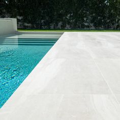 an empty swimming pool surrounded by trees and grass