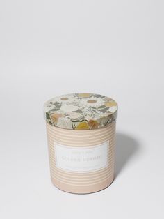 a candle that is sitting on top of a white surface with an orange and yellow flower pattern