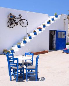 there is a table and chairs in front of the house with flowers on the stairs