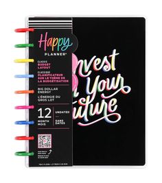 a spiral notebook with the words happy planner next to it and colorful markers on top