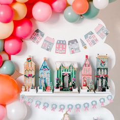 a birthday party with balloons, cake and decorations on a shelf in front of the wall