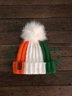 an orange, white and green knitted hat with a pom - pom