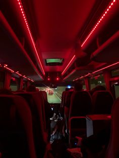 the inside of a bus with red lights and people sitting in seats on either side