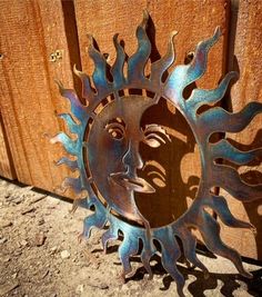 a metal sun face sitting on top of a wooden fence