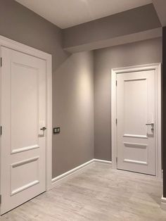 an empty room with two white doors on the wall and another door in the floor