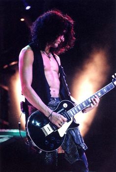 a man with long hair playing an electric guitar