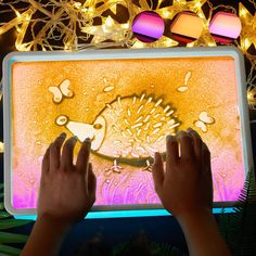 two hands are touching an electronic screen with lights in the background and decorations around it