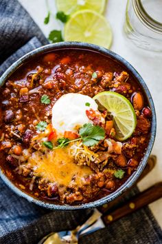 a bowl of chili with sour cream and cilantro garnish on top