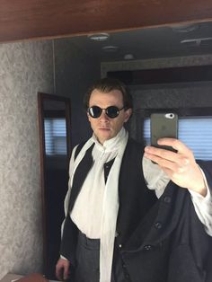 a man taking a selfie in front of a mirror wearing sunglasses and a suit