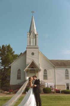 a bride and groom standing in front of a church