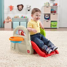 a toddler sitting on top of a toy car in the middle of a room