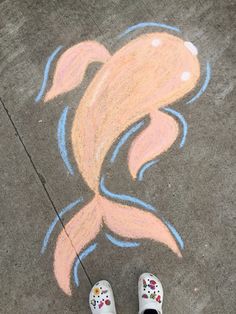 a pair of white shoes sitting on top of a sidewalk next to a chalk drawing of a fish