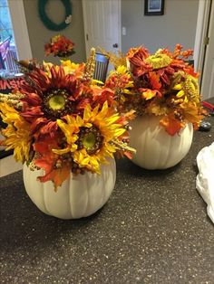 two white pumpkins with flowers in them sitting on a counter