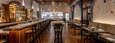 the interior of a restaurant with tables and chairs lined up against the wall, along with bar stools