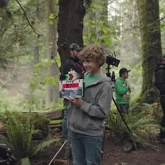 a man standing in the woods holding a camera